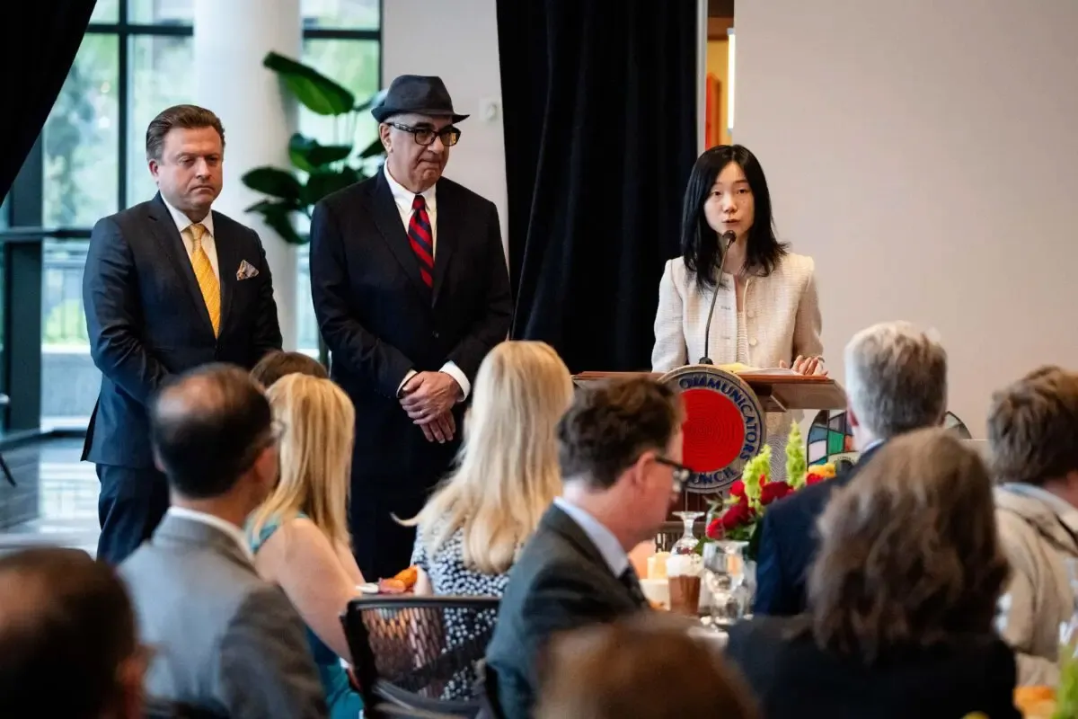 With Epoch Times senior editor Jan Jekielek (L) and reporter Dan Berger (2nd L) beside her, reporter Eva Fu accepts her 2025 Wilbur Award